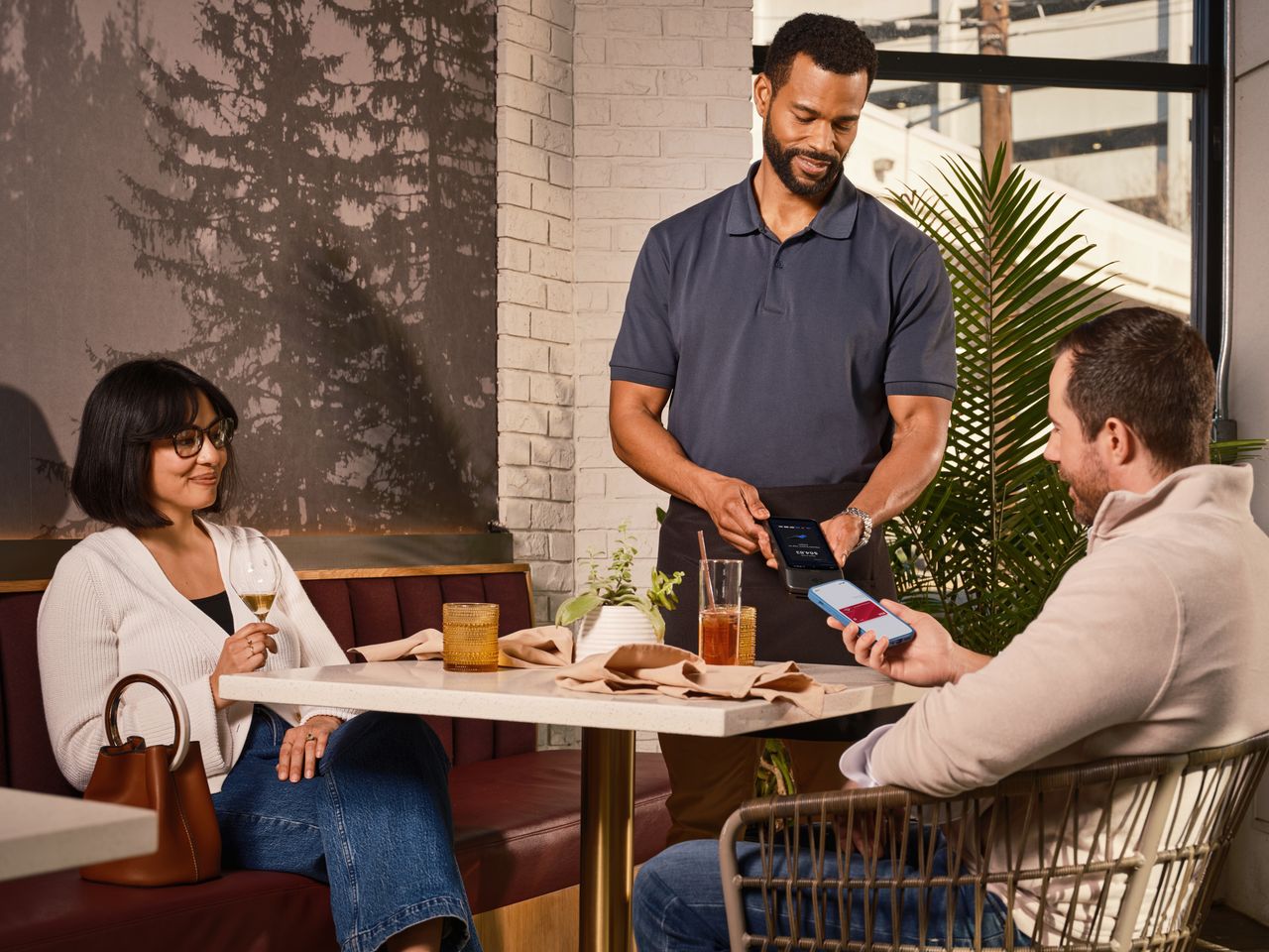 Serveur encaissant un paiement sans contact à table avec un logiciel de restauration moderne